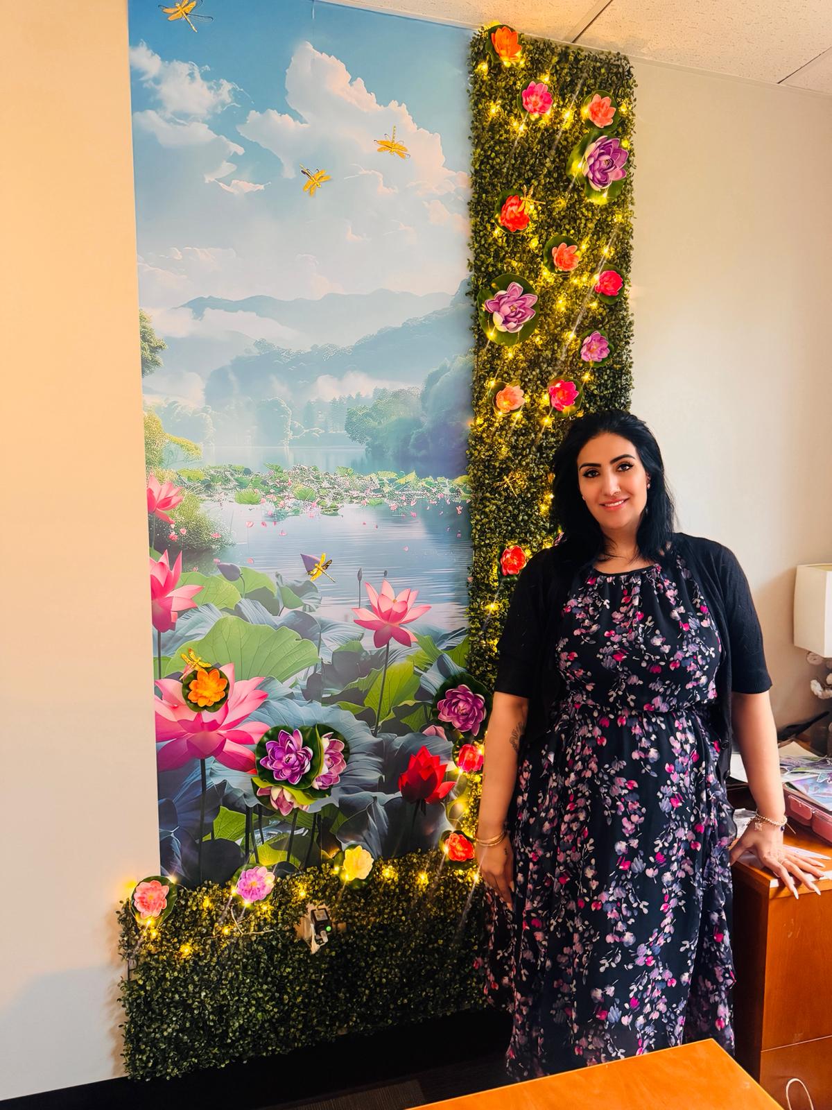 Rubina standing next to a lotus mural